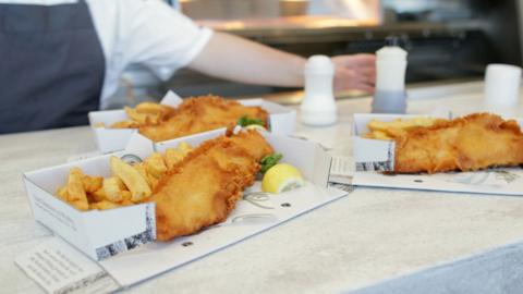 Some portions of fish and chips with some salt and vinegar alongside