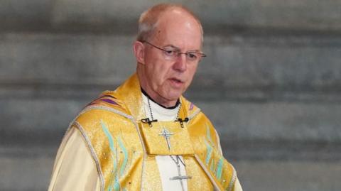 Justin Welby, wearing glasses and yellow robes.