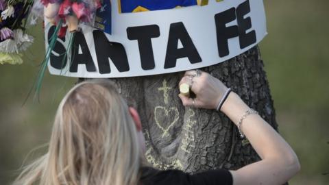 Student chalks a message on a tree outside Santa Fe High School, TX 19 May 2108