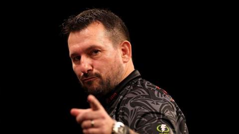 Jonny Clayton points with the index finger of his left hand as he celebrates at a Premier League darts event
