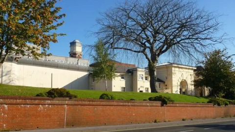 A general view of HMP Winchester, a Victorian prison seen from a roadside.