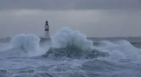 A lighthouse with crashing waves in stormy weather. 