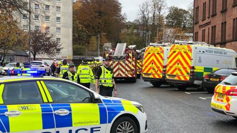 Emergency services at Overtoun Court - police cars, fire engines and incident response unit vans are there, while several police officers are standing around