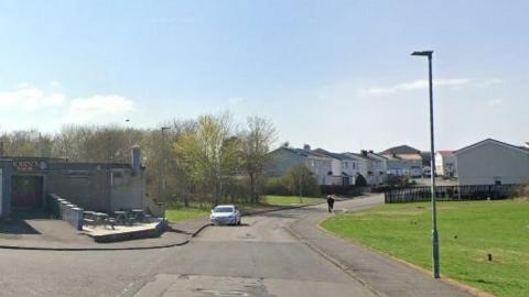 A road with a bar on the left and side and houses 