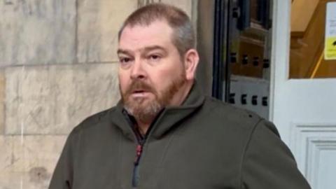 Russell Mason, a man with beard, leaving court in a zipped up jacket.