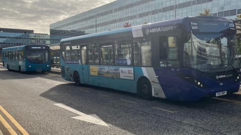 A picture of two Arriva buses, one in front of the other, outside station square in Milton Keynes.