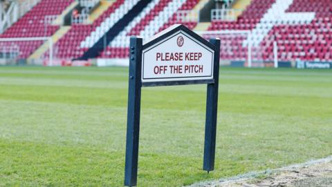 A please keep off the pitch sign by the side of the pitch at Woking's Laithwaite Community Stadium