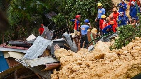 Rescue workers digging into rubble at the site of the landslide