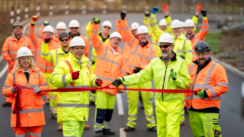 Image of councillors and the contracted team cutting a red ribbon across the new road 