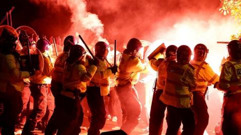 Legia Warsaw fans let off flares as they clash with police officers outside the stadium before the match