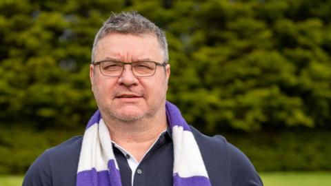 Daren Young - short dark hair and glasses wearing a Daventry Town scarf