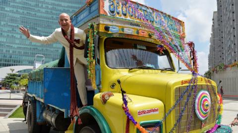 US founder and CEO of Amazon.com Jeff Bezos poses on a lorry after handing over a two billion dollar cheque to Indian Vice President and Country Manager of Amazon.in, Amit Agarwal (unseen) in Bangalore on September 28, 2014.