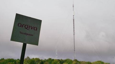 Tacolneston transmission mast which is located in a field in Tacolneston in Norfolk. The site broadcasts national radio and television to the East of England. A sign for the company is next to the mast which says arqiva Tacolneston in red writing