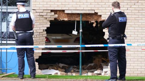 Police officers stand beside the debris and damage to the Beacon Church of England Primary School