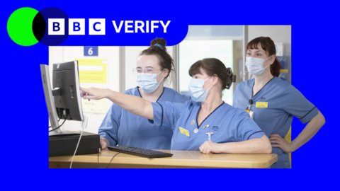 Three nurses in blue uniforms and wearing face masks pointing at a computer monitor