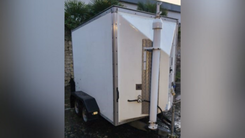 A non-descript white trailer, that has a large white mast on the front.