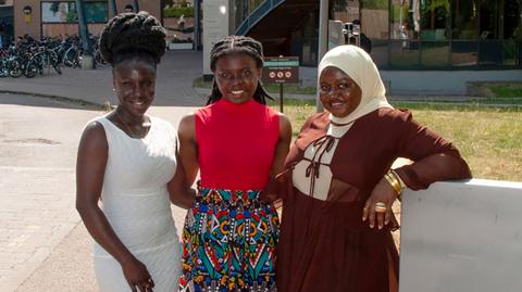Francisca Arhinful, Jemimah Mensah and Fadila Issah, lined up together and smiling broadly. They are standing outside Cambridge University's Faculty of Education. 