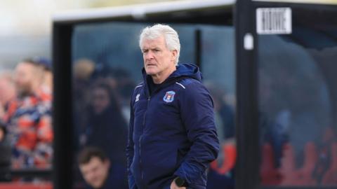 Mark Hughes in his Carlisle hooded jacket, stood on the touchline at Truro 