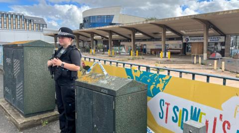 Police officer in front of the derelict Exeter coach and bus station