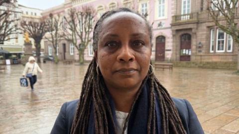 Deputy Beatriz Porée is pictured in Jersey's Royal Square. She is wearing a blue scarf and a black blazer. 