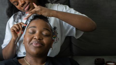 A woman styles another woman's hair