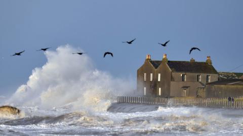 A house next to the road at Dubmill Point, near Allonby, is hit by spray from big waves on the Irish Sea.