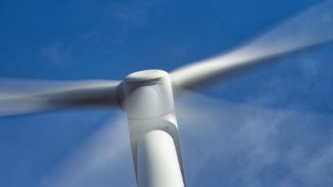 A wind turbine in close up against a blue sky