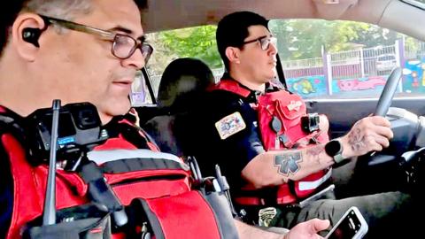 The two paramedics both wearing red stab vests and cameras, in their ambulance, on their way to an incident