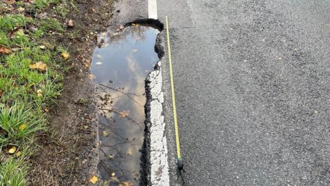 Tape measure lying next to a pothole reported to Hampshire County Council. 