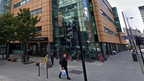 The corner of Liverpool Civil & Family Court which has light brown cladding and a staircase with glass panels. 