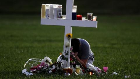 young boy sits a memorial cross that honors victims of the mass shooting at Marjory Stoneman Douglas High School, at Pine Trail Park on February 16, 2018 in Parkland, Florid