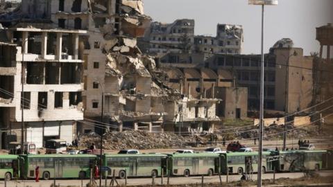 Buses wait in Ramouseh, Aleppo, 15 Dec