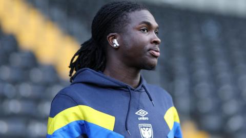 Osman Foyo wearing an AFC Wimbledon-branded hoodie