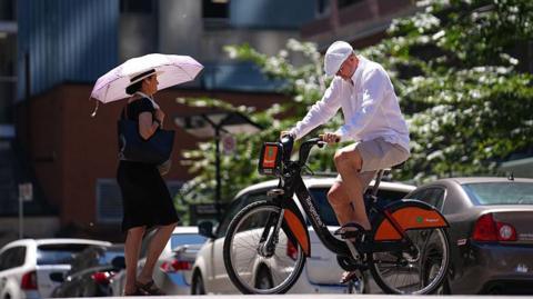  A woman walks with an umbrella to protect herself from the sun in Toronto, Ontario 