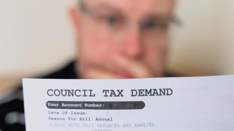 A worried man looking at his council tax bill.