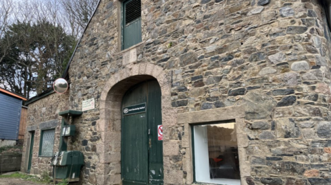 The front of Sark Electricity. The door is green and there's a window to the right.