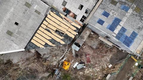 A warehouse from above where damage to the roof can be seen.