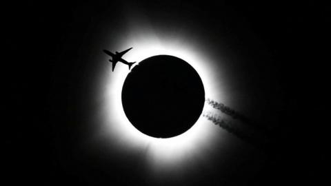A photograph of a plane, passing near the total solar eclipse, taken in Bloomington, Indiana
