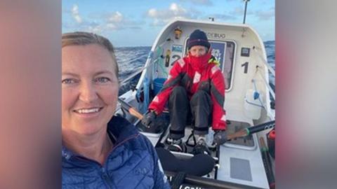 Emma Wolstenholme and a crew member on board their small rowing boat. She is in blue while her colleague wears a red overcoat and beanie hat