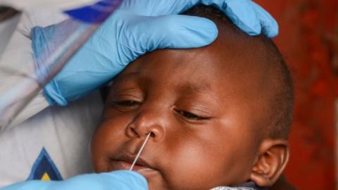 A health worker performs a nasal swab test on an infant in Nairobi, Kenya, in May 2020.