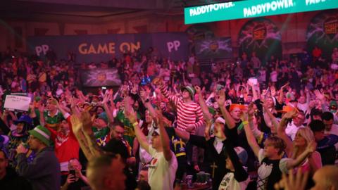 A crowd of people in a room with their arms raised