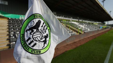 A shot of the corner flag with the Forest Green Rovers badge on it with the New Lawn stadium in the background