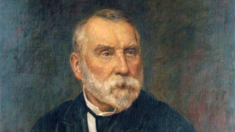 A portrait of a man - Sir Edward Watkin - sat facing slightly to the right. He is painted wearing a black jacket and a white shirt. He has a grey beard and receding grey hair. 