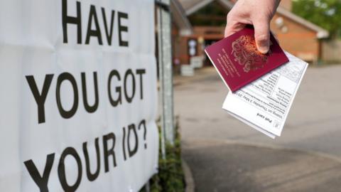 A person outside a polling station with their passport