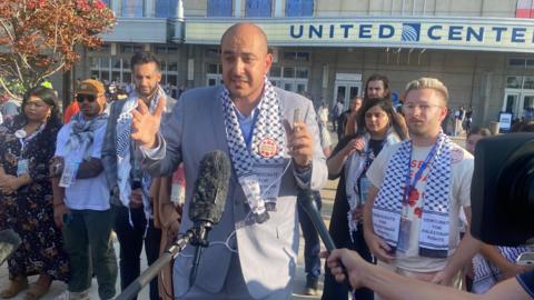 A group of people gathered in front of microphones outside the United Center in Chicago