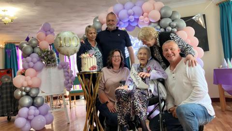 Olive Porritt in a lilac cardigan surrounded by her family