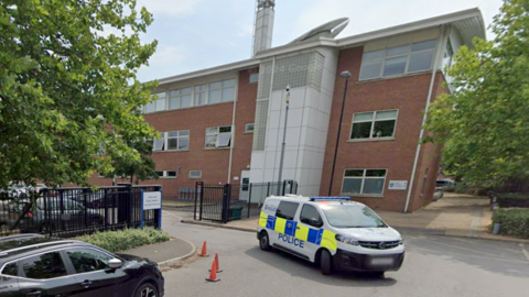 A police van pulls out of a gated car park behind Abingdon's brick-built police headquarters