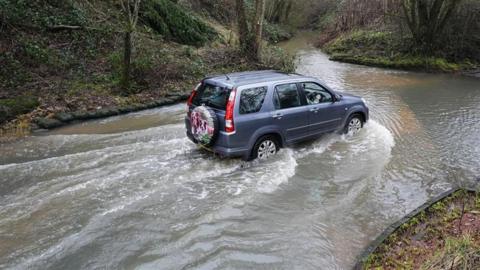 A blue SUV drives through a flooded road in Houndsfield Lane, Birmingham, on Monday.
