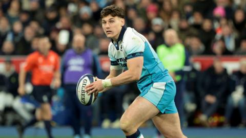 Tom Jordan holding the ball in two hands during a match for Scotland
