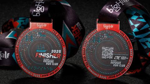 The Big Half finisher medal for 2025. It is red, black and teal. 